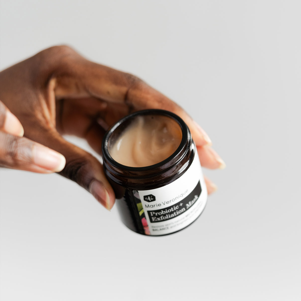 Hand holding jar of Marie Veronique Probiotic + Exfoliation Mask 1.7 oz / 50ml. Restore skin’s natural MICROFLORAL BALANCE and brighten with ENZYMES. Microbiome-friendly