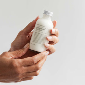 Marie Veronique's NEW Body Barrier Emulsion 4 oz - Human hands holding a bottle of the product showing the size of the bottle in the hand, fitting easily into your hand.